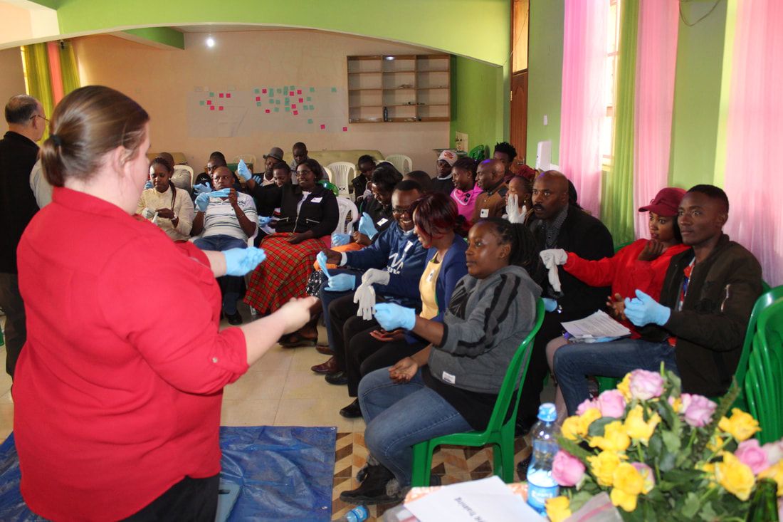 Trainer demonstrating safe glove technique to a first aid class